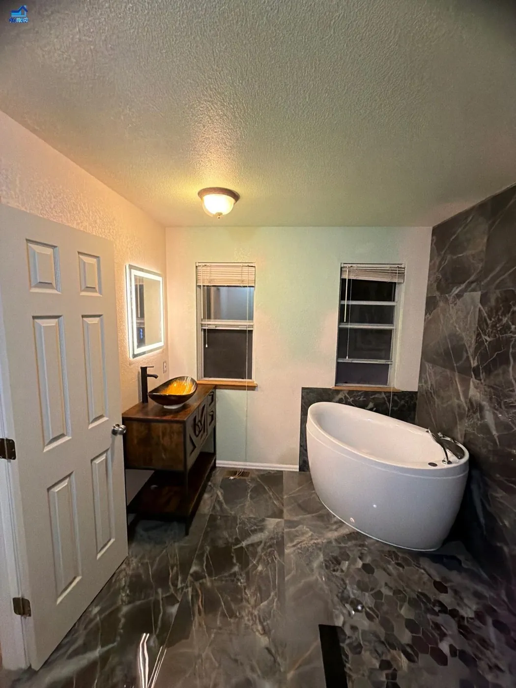 Black-and-white checkerboard floor bathroom with a freestanding tub, grab bar and glass shower