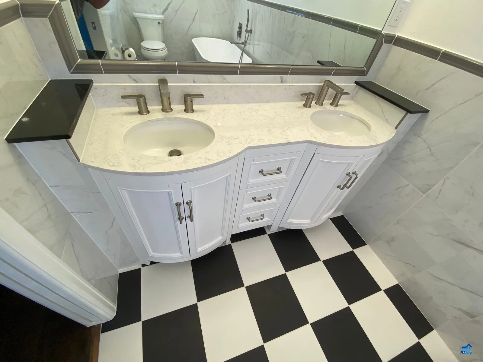 Marble-tiled bathroom with a glass-enclosed walk-in shower and black hexagon mosaic shower floor